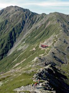 絶 景 北岳から間ノ岳(写真左奥)までの稜線を望む。手前の登山者の行く手には北岳山荘(写真中央)が見える