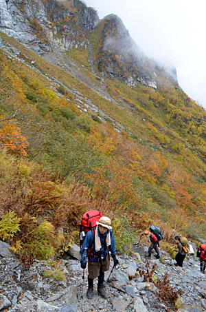 北岳バットレスの岩壁と紅葉を間近に見ながら進む登山者