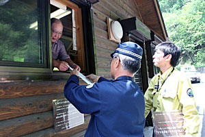 夜叉神の森駐車場周辺でクモマツマキチョウの食草ともなる高山植物の盗掘への注意を呼び掛けるチラシを配る環境省職員と南アルプス署員=南アルプス市芦安芦倉