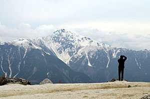 薬師岳周辺から北岳に向けてカメラを構える登山者。北岳の荒々しい山肌を望むことができる