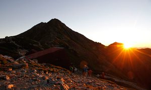 ＜照らされる峰＞　昇る朝日に照らし出される北岳。太陽が徐々に姿を現すと、周辺はオレンジ色に染まり、登山者から歓声が上がった